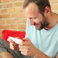 stock-footage-young-happy-man-playing-games-on-smartphone